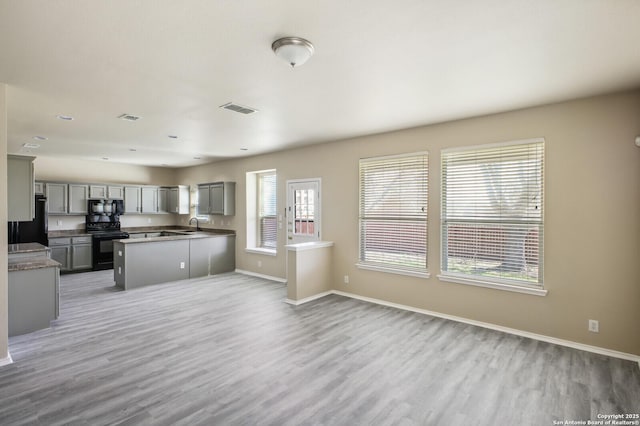 kitchen featuring baseboards, visible vents, light wood-style flooring, gray cabinetry, and black appliances