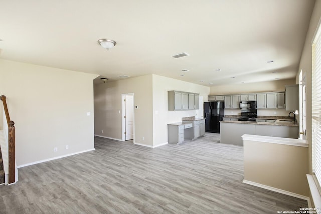 unfurnished living room with visible vents, light wood-style flooring, baseboards, and a sink