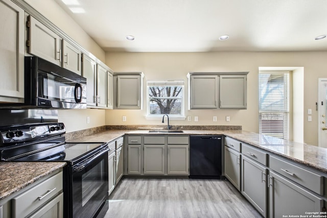 kitchen with a wealth of natural light, gray cabinetry, black appliances, and a sink