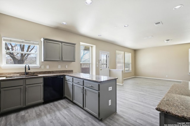 kitchen with visible vents, gray cabinetry, a sink, a peninsula, and dishwasher