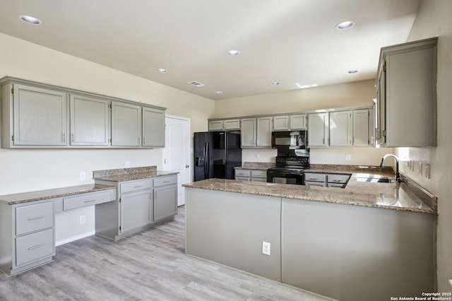 kitchen featuring black appliances, light stone counters, a peninsula, and gray cabinets