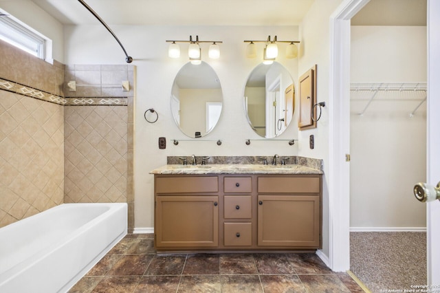 full bathroom featuring double vanity, a spacious closet, baseboards, and a sink