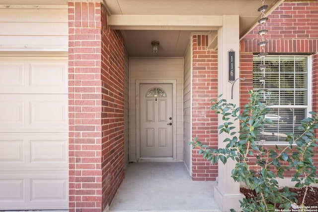 property entrance with a garage and brick siding