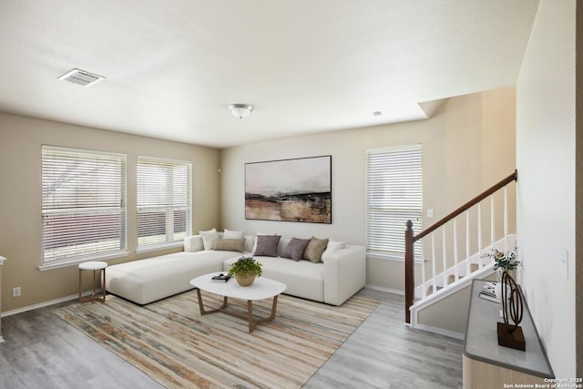 living area with visible vents, stairs, baseboards, and wood finished floors