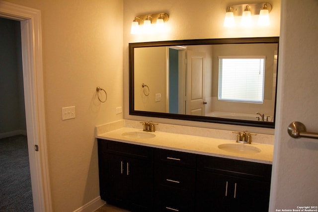 full bathroom with a sink, baseboards, a bath, and double vanity