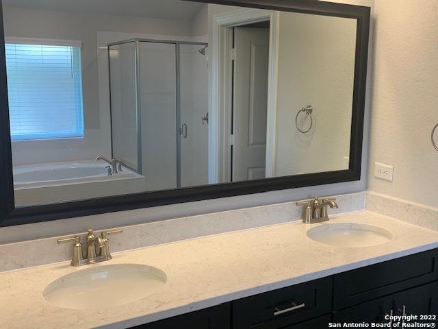 bathroom with a shower stall, double vanity, and a sink