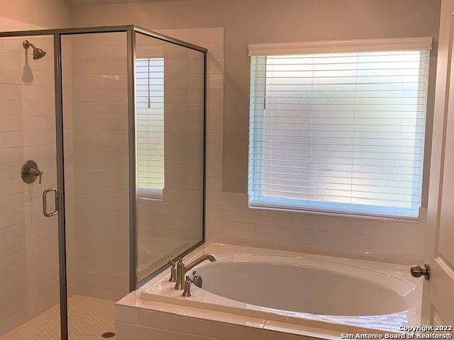 bathroom featuring a shower stall and a bath