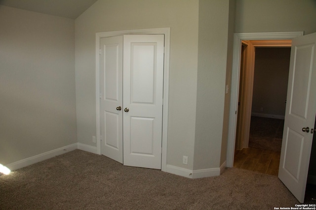 unfurnished bedroom featuring a closet, carpet flooring, baseboards, and vaulted ceiling