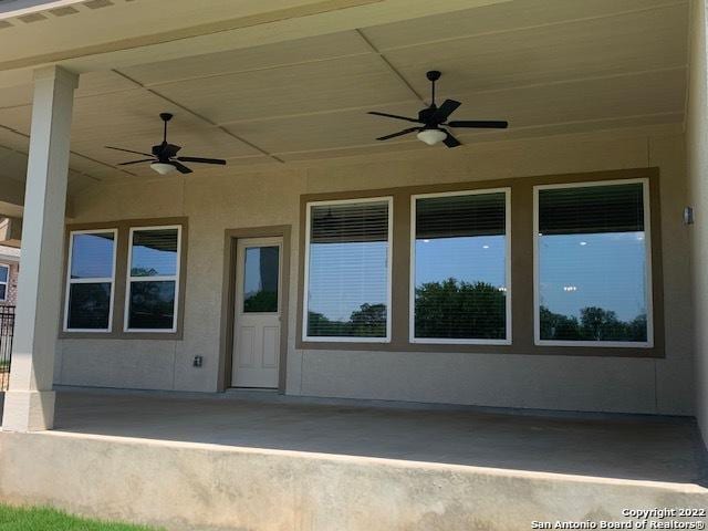 property entrance with visible vents, stucco siding, and ceiling fan