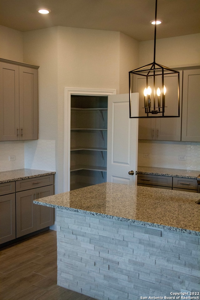 kitchen featuring light stone counters, gray cabinetry, and decorative light fixtures