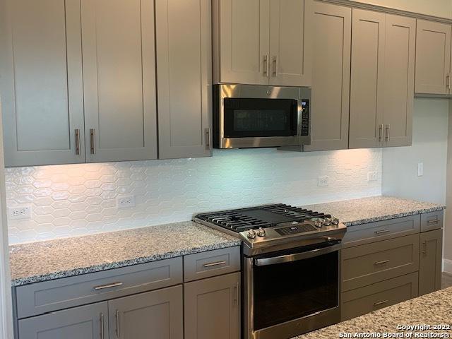 kitchen featuring light stone counters, decorative backsplash, appliances with stainless steel finishes, and gray cabinetry