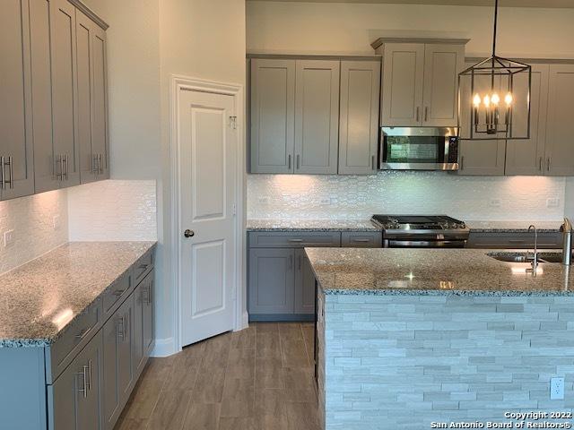 kitchen featuring stone counters, gray cabinetry, appliances with stainless steel finishes, and a sink