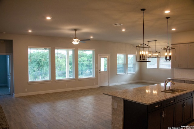 kitchen with a sink, open floor plan, recessed lighting, and light wood finished floors