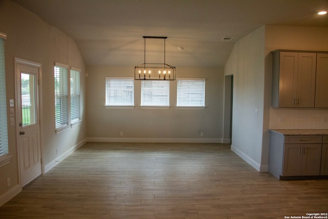 unfurnished dining area featuring visible vents, a healthy amount of sunlight, light wood-style flooring, and lofted ceiling