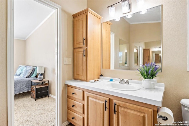 ensuite bathroom with toilet, ensuite bathroom, crown molding, baseboards, and vanity