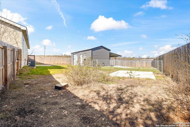 view of yard featuring central AC unit, a fenced backyard, and an outbuilding