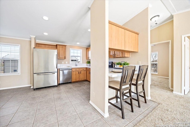 kitchen with light countertops, ornamental molding, light brown cabinetry, and stainless steel appliances