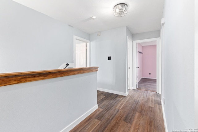 corridor featuring baseboards and dark wood-style flooring