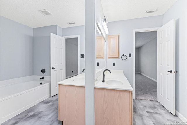 bathroom featuring a sink, visible vents, a garden tub, and double vanity