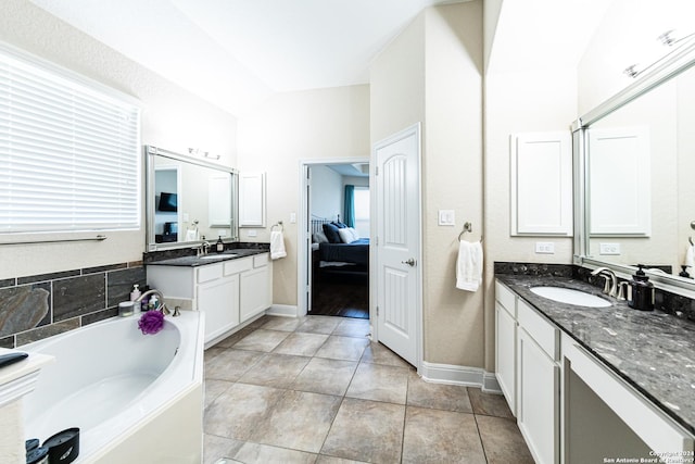 ensuite bathroom featuring a bath, tile patterned flooring, two vanities, and a sink