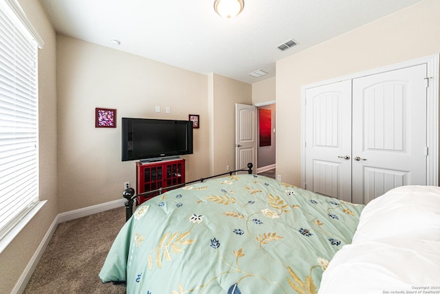 carpeted bedroom featuring multiple windows, baseboards, visible vents, and a closet