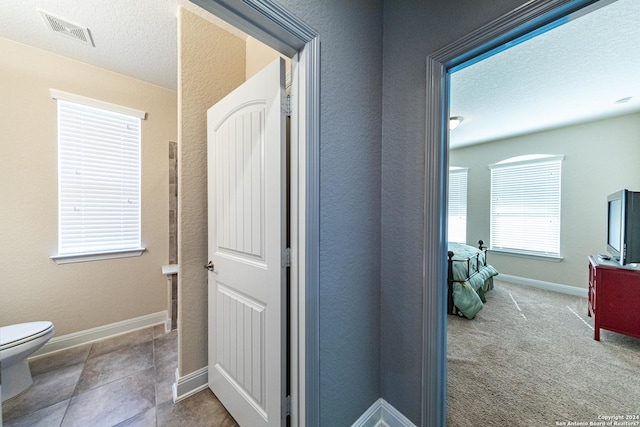 interior space with carpet, baseboards, visible vents, and a textured ceiling