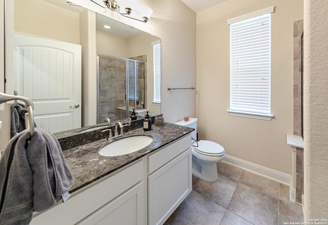 bathroom featuring vanity, a shower stall, toilet, and baseboards