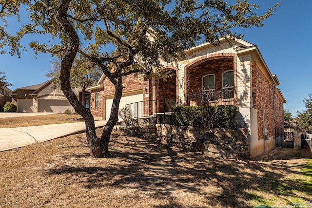 view of front of property with a garage, brick siding, driveway, and fence