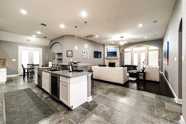 kitchen featuring wine cooler, a kitchen island with sink, white cabinets, and a sink