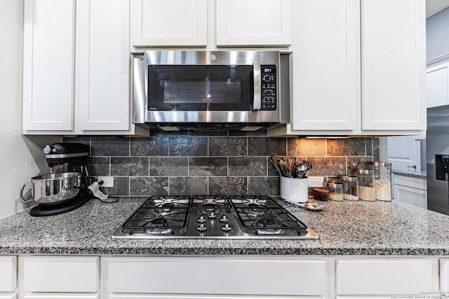 kitchen with stone countertops, stainless steel appliances, backsplash, and white cabinetry