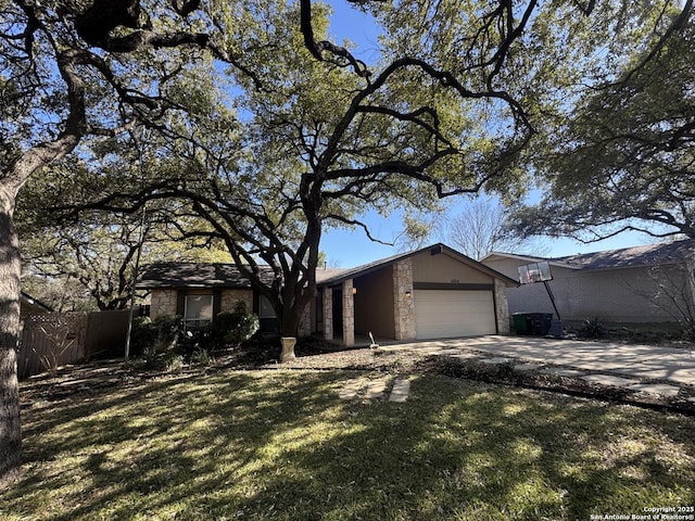 view of front of home featuring fence, an attached garage, a front lawn, concrete driveway, and stone siding