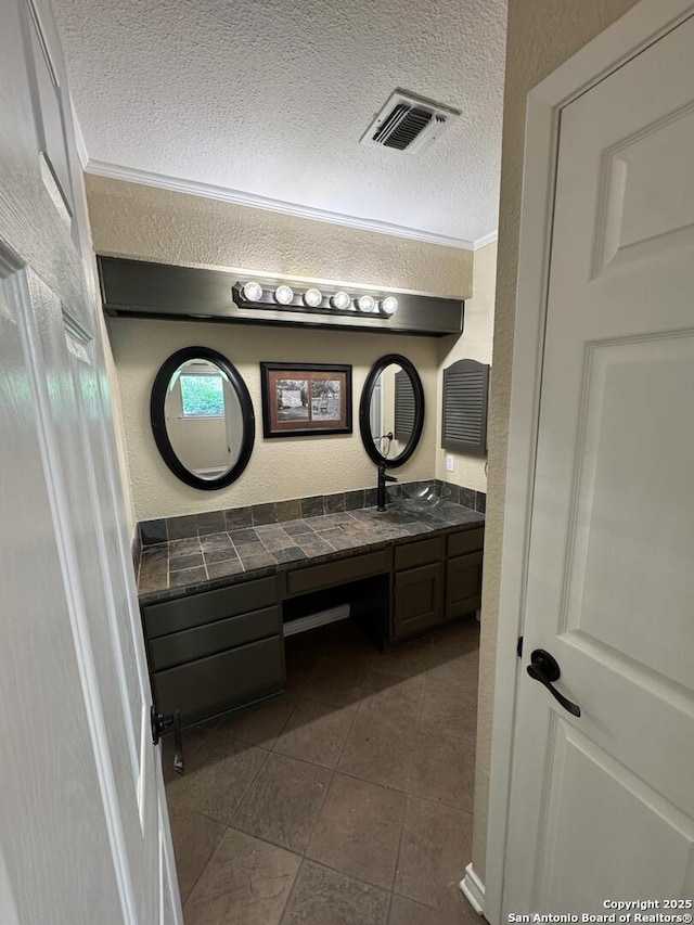 bathroom with visible vents, vanity, a textured wall, tile patterned floors, and a textured ceiling