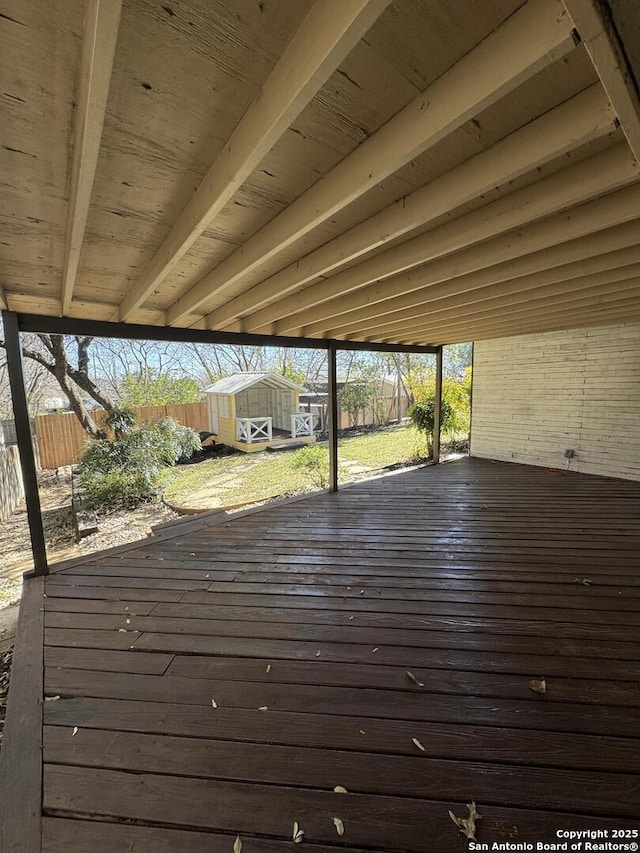 wooden terrace with a storage shed, fence, and an outdoor structure