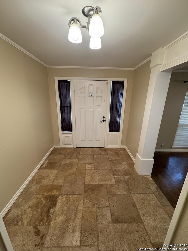 foyer entrance with stone tile floors, an inviting chandelier, baseboards, and ornamental molding