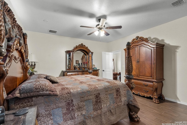 bedroom featuring visible vents, baseboards, ceiling fan, and wood finished floors