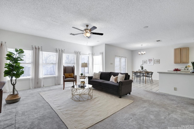 living room featuring light carpet, ceiling fan with notable chandelier, a textured ceiling, and a wealth of natural light