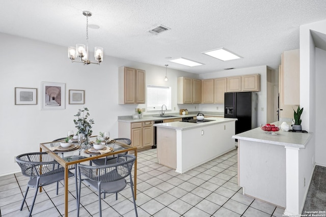 kitchen featuring a center island, light brown cabinets, visible vents, and a sink