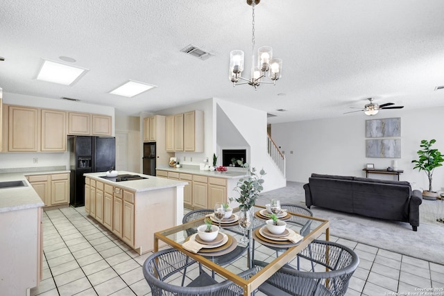 kitchen featuring visible vents, light brown cabinets, open floor plan, light countertops, and black appliances