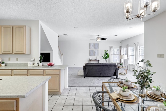 kitchen featuring light brown cabinetry, open floor plan, light countertops, light tile patterned floors, and ceiling fan with notable chandelier