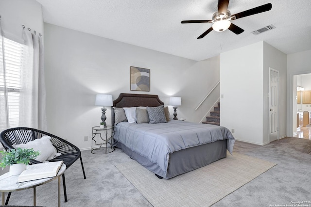 bedroom with visible vents, baseboards, light carpet, ensuite bathroom, and a textured ceiling