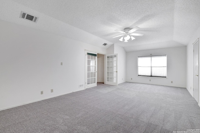 empty room with visible vents, lofted ceiling, ceiling fan, french doors, and light colored carpet