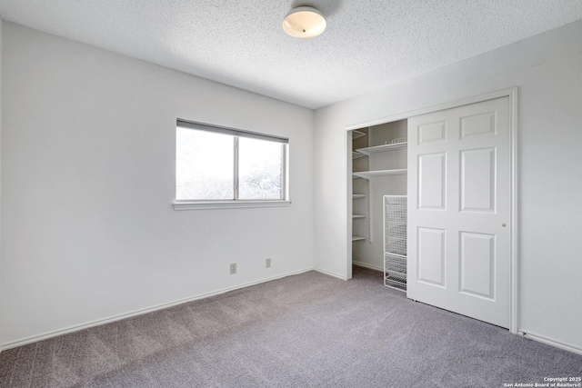 unfurnished bedroom featuring a closet, baseboards, a textured ceiling, and carpet