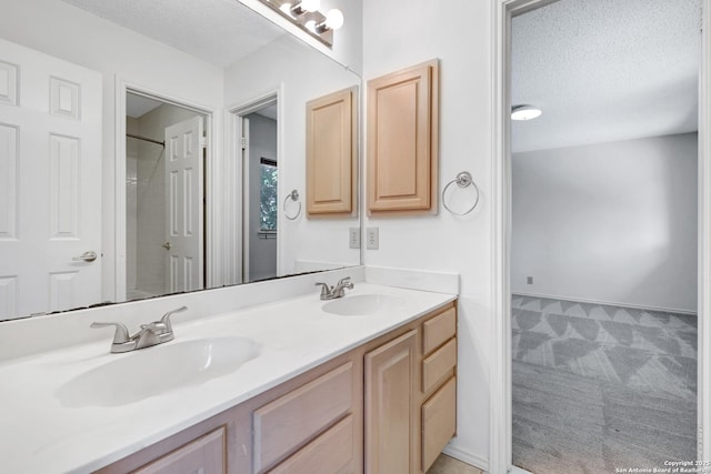 full bathroom with double vanity, a textured ceiling, walk in shower, and a sink