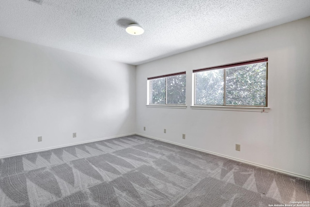 carpeted spare room with baseboards and a textured ceiling