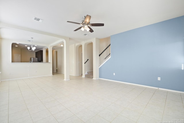 unfurnished living room featuring visible vents, ceiling fan with notable chandelier, arched walkways, baseboards, and stairs