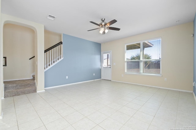 unfurnished room with stairs, light tile patterned floors, a ceiling fan, and baseboards