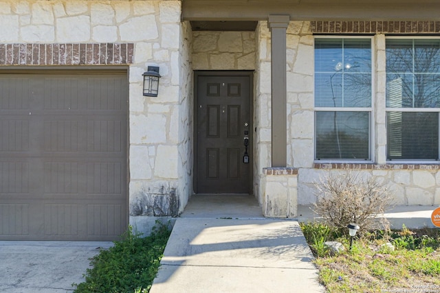 view of exterior entry with a garage and stone siding