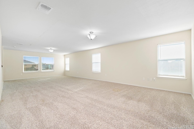 carpeted empty room featuring visible vents and baseboards