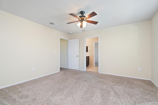 unfurnished bedroom featuring visible vents, baseboards, ceiling fan, light colored carpet, and ensuite bathroom