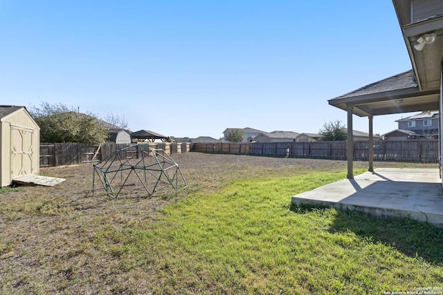 view of yard featuring a storage unit, a patio, an outdoor structure, and a fenced backyard